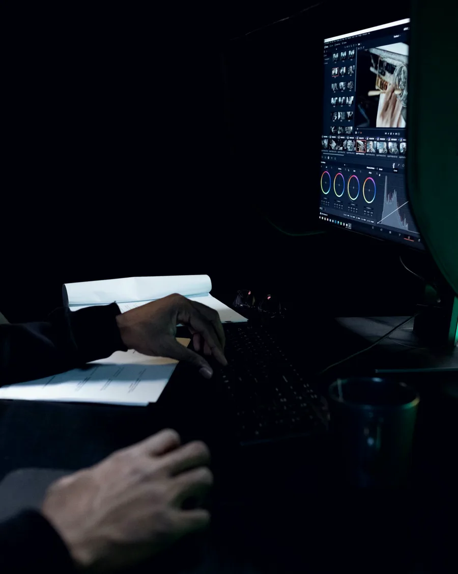 An editor colour grading footage on a monitor in a dark room